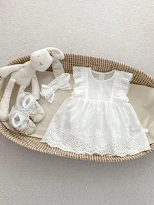 Detail of white cotton baby dress set with lace headband and shoes in a basket