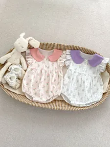 Détail de barboteuses fleuries pour bébé avec col Claudine et manches à volants dans un panier