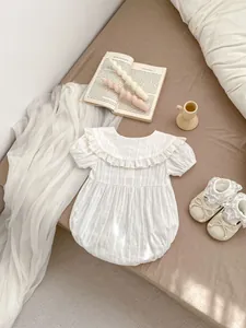 Close-up of white baby romper with ruffled collar and bubble sleeves on a soft background