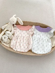 Détail d'un body floral pour bébé avec manches volantées et chaussures en dentelle dans un panier