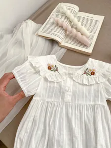 Detail of floral embroidery on a white puff sleeve baby romper with ruffle collar