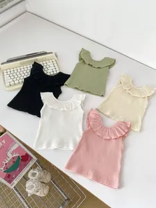Detail of five ribbed sleeveless baby tops with ruffled collars in varied colors