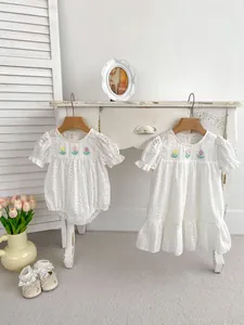 Detail of white eyelet cotton baby romper featuring colorful tulip embroidery