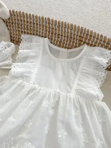 Detail of white cotton baby romper with floral embroidery, flutter sleeves and lace trim
