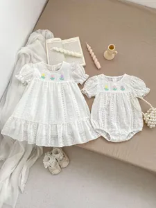 Close-up of white eyelet cotton dress with colorful floral embroidery and lace trim