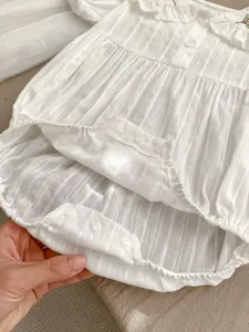 Detail of baby romper with embroidered Peter Pan collar and vertical stripe texture