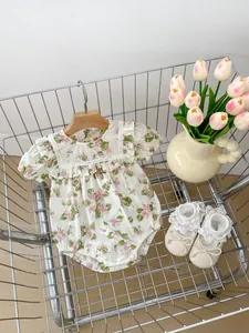 Detail of floral baby bodysuit with lace trim and matching shoes in a rustic setting
