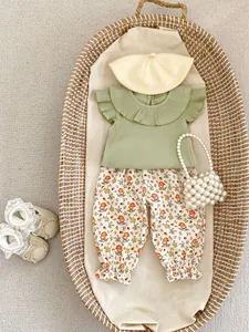Flat lay of baby girl sage green flutter sleeve top and mushroom print pants in a basket