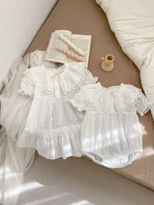 Detailansicht der Blumenstickerei und des Rüschenkragens am weißen Baby-Strampler