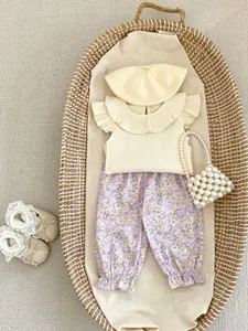 Flat lay of baby girl flutter sleeve top with floral pants, hat and accessories