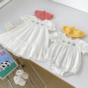 White cotton baby bodysuit and dress set with floral embroidery and lace details