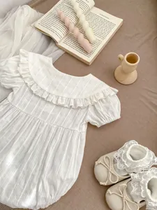 Flat lay of baby white bodysuit with ruffled collar and lace-up infant walking shoes