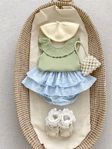 Close-up of sage green ruffled sleeveless top and floral tiered skirt set in a basket