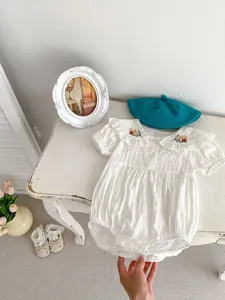 Close-up of floral embroidery on the ruffle collar of a white baby girl romper