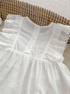 Detailed back view of white cotton baby dress showing floral embroidery and button closure