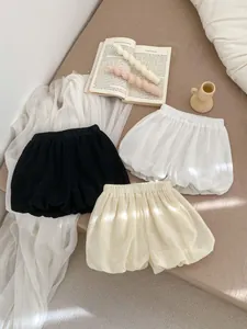 Detailed flat lay of three pairs of toddler bloomers in black, white, and beige cotton