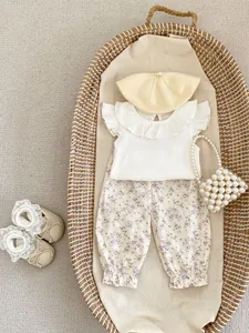 Flat lay of baby girl floral trousers and sleeveless top set in a woven basket