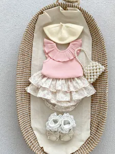 Flat lay of pink ruffled top with floral layered bloomer and pearl accessories