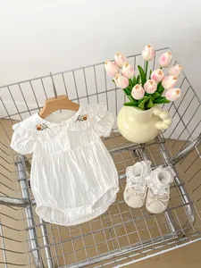 Detail view of baby girl romper with floral embroidery and lace collar in a basket