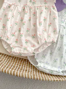 Détail d'un body bébé à fleurs avec taille à volants et boutons-pression sur tissu coton