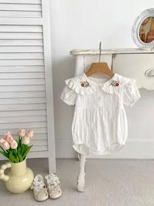 Detail of baby white cotton romper with Peter Pan collar and delicate floral embroidery