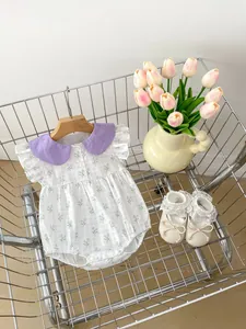 Détail d'un barboteuse bébé à fleurs avec col Peter Pan violet et chaussures en dentelle