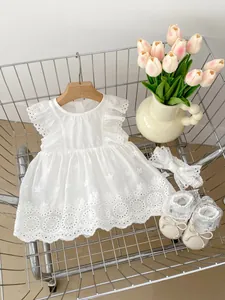 Flat lay of baby girl white cotton dress with bow headband and soft princess shoes