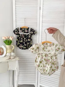 Detail of baby floral lace rompers with delicate ruffles on white wooden background