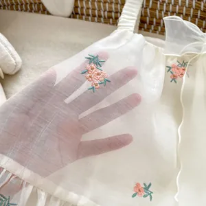 White embroidered baby tulle bodysuit with floral patterns and ruffled shoulder straps