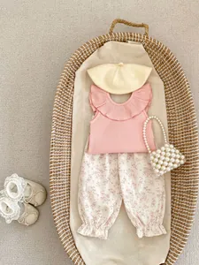 Flat lay of pink ruffle top and floral lantern pants set for toddler girls in a basket