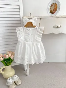 Detail of white cotton baby dress with lace embroidery and matching bow headband
