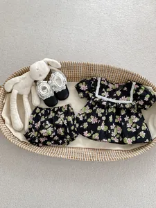 Flat lay of floral baby girl set with top, bloomers and shoes in a wicker basket