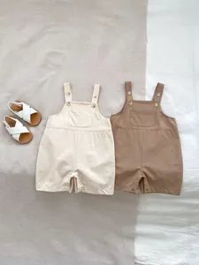Detail of baby romper shorts showing adjustable button straps and cotton-linen texture