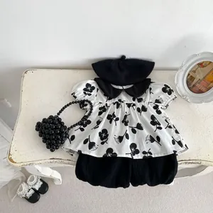 Close-up of floral print puff sleeve top and black lantern shorts set on a white desk