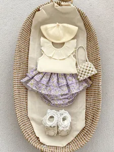 Flat lay of baby girl beige knit top and floral tiered skirt with matching accessories