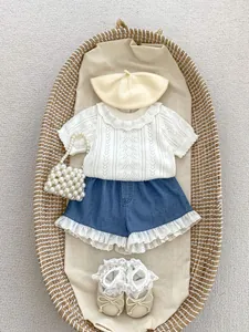 Flat lay of baby girl hollow knit top and lace denim shorts with matching accessories