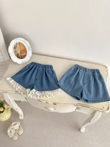 Detailed view of girls blue denim shorts featuring delicate white lace trim and elastic waist