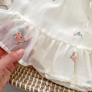 Detail of pink floral embroidery and layered ruffle mesh fabric on baby girl romper