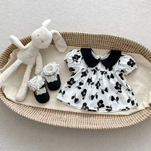 Close-up of baby girl floral dress with Peter Pan collar and matching lace shoes
