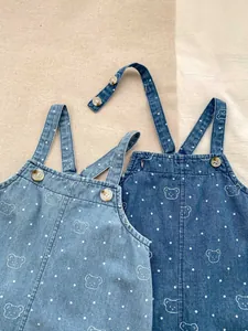 Detailed view of baby denim overalls with cute bear prints and adjustable button straps