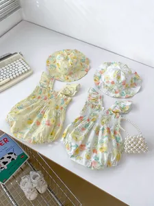 Detail von Baby-Bodys mit Blumenmuster und passenden Rüschenhüten aus gelber Baumwolle