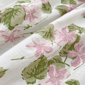 Floral print cotton baby bodysuit with pink flowers and green leaves on white fabric