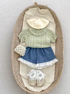 Flat lay of baby girl knit top with hollow patterns and denim skirt with lace trim