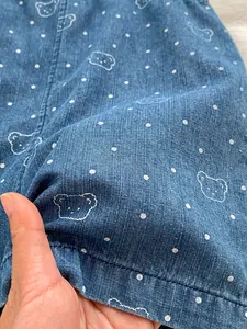 Detail of blue denim fabric with white polka dots and cute bear patterns for baby rompers