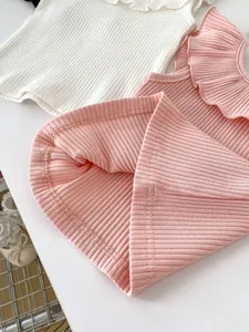 Detail of ruffled collar and ribbed texture on two sleeveless baby girl tops