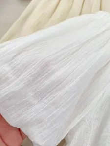 Detailed close-up of white breathable crinkle fabric texture for summer girls' shorts