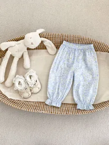 Pantalon fleuri pour bébé fille et chaussures à nœud posés sur un berceau tressé