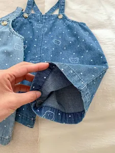 Detail of baby denim overalls featuring cute white bear prints and polka dot pattern