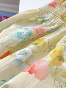 Detailaufnahme von Baumwollstoff mit Orangen-Blumenmuster und elastischen Falten