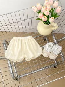 Detailed shot of cream puff bloomers and lace bow shoes in a stylized metal cart